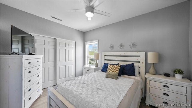 bedroom with ceiling fan, light hardwood / wood-style flooring, and a closet