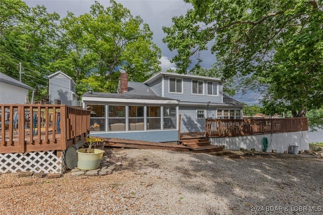 back of house featuring a sunroom, a chimney, and a deck