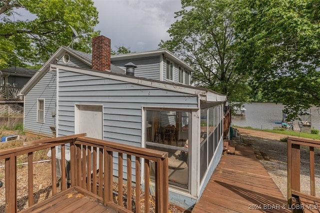 wooden deck featuring a water view and a sunroom