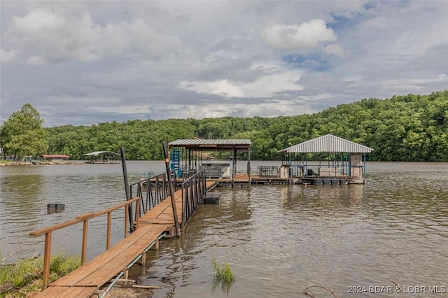 view of dock featuring a water view, boat lift, and a forest view