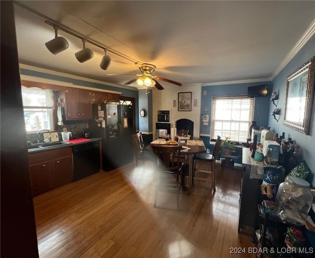 kitchen with a sink, black appliances, crown molding, and dark wood-style flooring