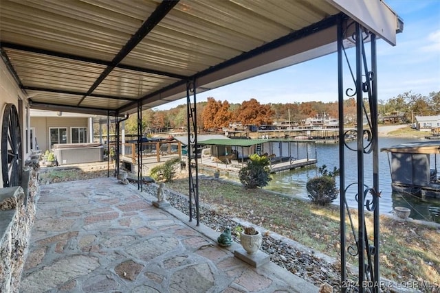 view of patio / terrace featuring a water view, a dock, and a hot tub