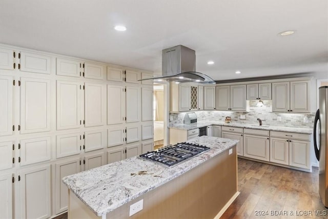 kitchen featuring a center island, light hardwood / wood-style flooring, light stone counters, island exhaust hood, and stainless steel appliances