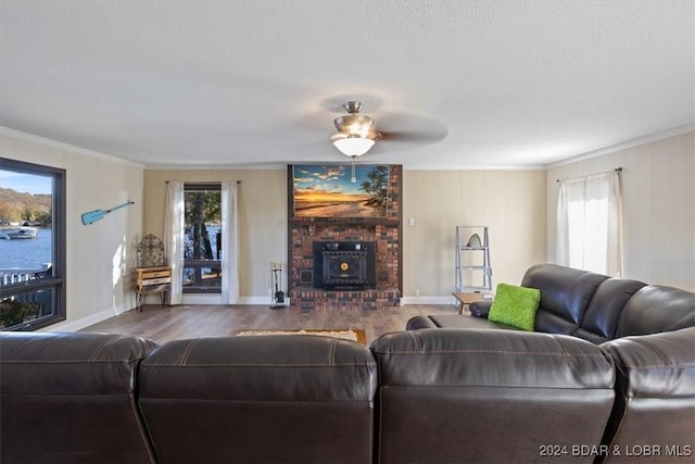 living room with hardwood / wood-style floors, a wood stove, ceiling fan, ornamental molding, and a textured ceiling