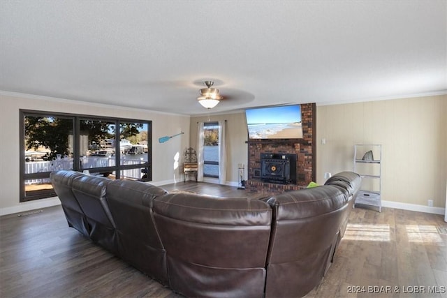 living room with hardwood / wood-style flooring, ceiling fan, a wood stove, and crown molding