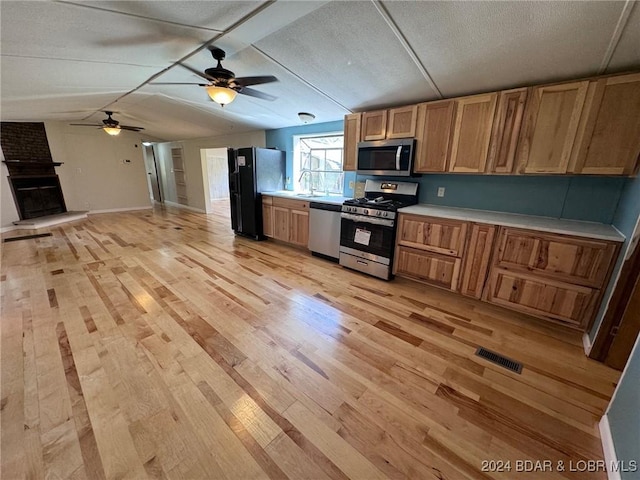 kitchen featuring sink, a brick fireplace, light hardwood / wood-style flooring, ceiling fan, and stainless steel appliances