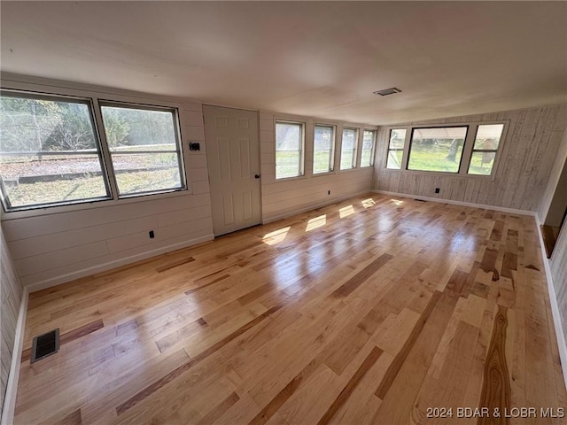 interior space with wooden walls, light hardwood / wood-style floors, and lofted ceiling