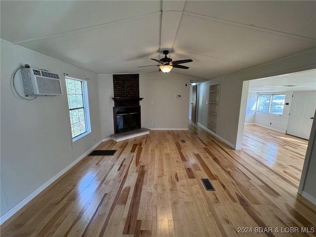 unfurnished living room with light hardwood / wood-style floors, a wall unit AC, and a wealth of natural light