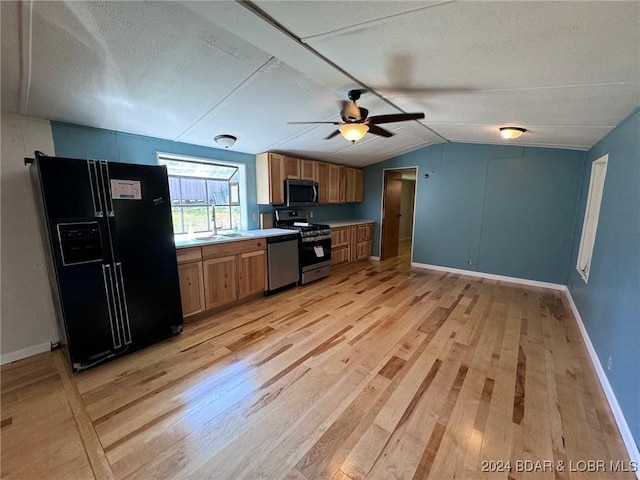 kitchen featuring appliances with stainless steel finishes, light wood-type flooring, a textured ceiling, vaulted ceiling, and ceiling fan