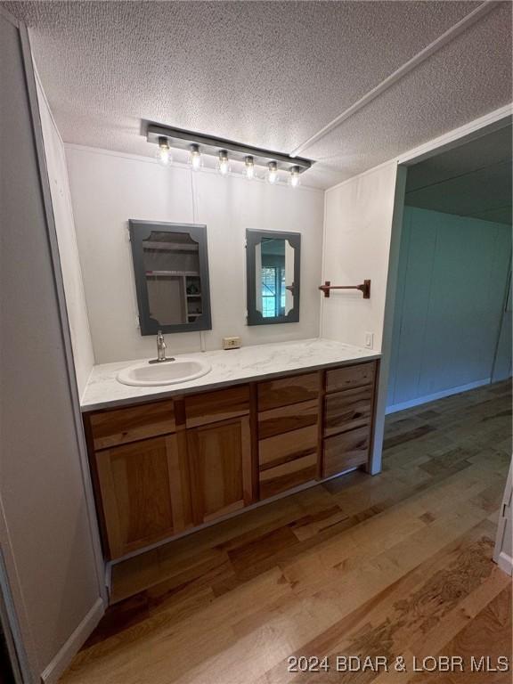 bathroom with hardwood / wood-style floors, vanity, a textured ceiling, and rail lighting