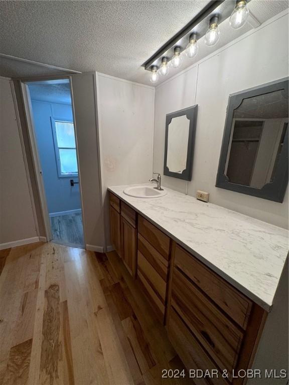 bathroom with hardwood / wood-style floors, vanity, and a textured ceiling