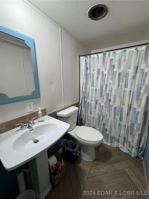 bathroom featuring parquet flooring, toilet, a textured ceiling, and walk in shower