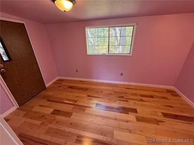 spare room with a textured ceiling and light hardwood / wood-style flooring