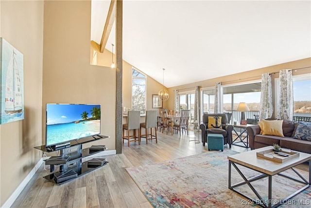 living room with beam ceiling, high vaulted ceiling, light hardwood / wood-style floors, and a notable chandelier