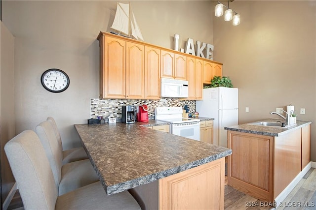 kitchen with sink, backsplash, kitchen peninsula, light hardwood / wood-style floors, and white appliances