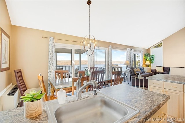 kitchen featuring plenty of natural light, vaulted ceiling, a sink, and an inviting chandelier
