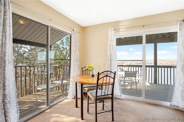 carpeted dining area featuring a water view