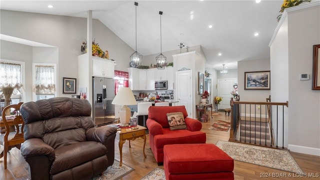 living room featuring high vaulted ceiling and light hardwood / wood-style flooring