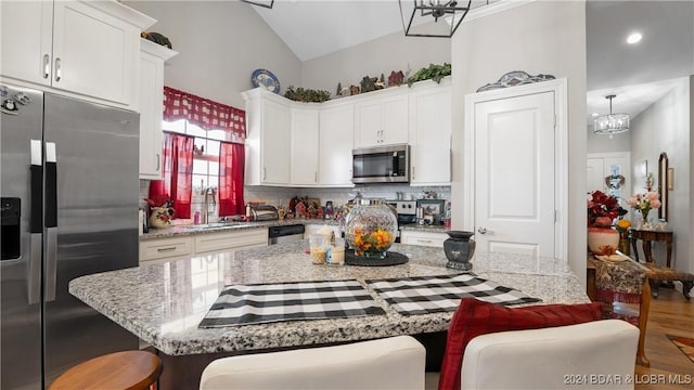 kitchen with white cabinets, a kitchen island, a kitchen bar, and stainless steel appliances