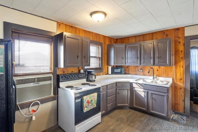 kitchen featuring sink, dark hardwood / wood-style flooring, wood walls, cooling unit, and black appliances