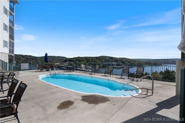 view of swimming pool with a water view and a patio