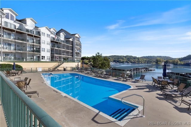 view of pool featuring a water view and a patio