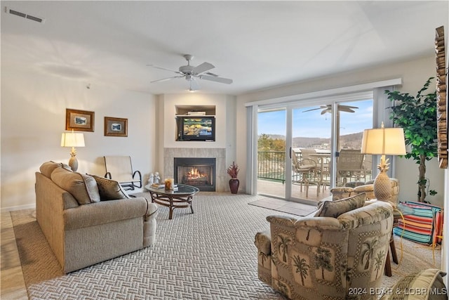 living room with ceiling fan and a tiled fireplace