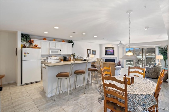 tiled dining area with ceiling fan, sink, and a tiled fireplace