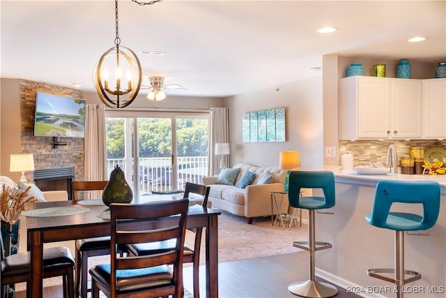 dining space with a notable chandelier, a stone fireplace, and dark hardwood / wood-style flooring