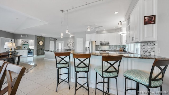 kitchen featuring white cabinetry, beverage cooler, dark stone countertops, kitchen peninsula, and appliances with stainless steel finishes