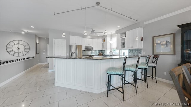 kitchen featuring white cabinets, dark stone counters, decorative light fixtures, and appliances with stainless steel finishes