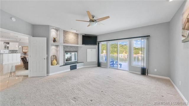 unfurnished living room with carpet, a large fireplace, and ceiling fan