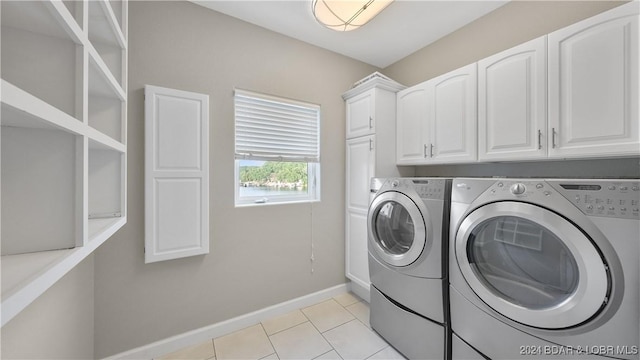 clothes washing area featuring washer and dryer, cabinets, and light tile patterned flooring