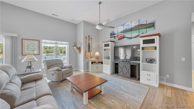 living room with ceiling fan, high vaulted ceiling, and light wood-type flooring