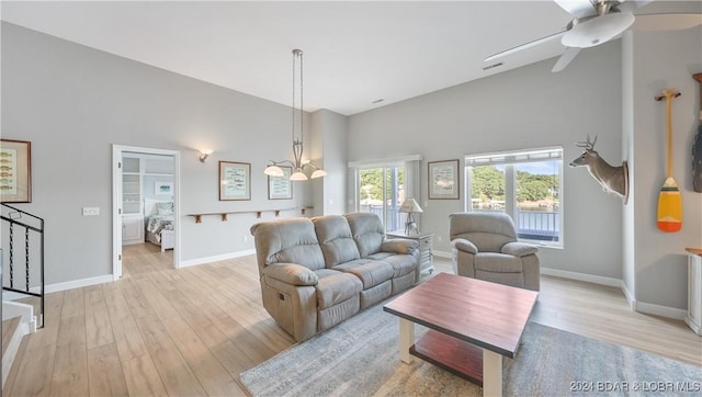 living room featuring light hardwood / wood-style flooring, a high ceiling, and ceiling fan with notable chandelier