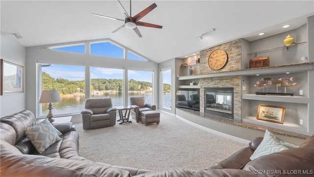 living room with a water view, a stone fireplace, a wealth of natural light, and carpet