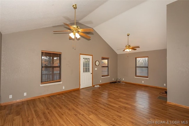 unfurnished living room featuring ceiling fan, a healthy amount of sunlight, lofted ceiling, and light hardwood / wood-style flooring