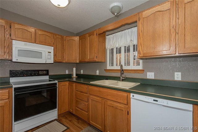 kitchen featuring a textured ceiling, wood-type flooring, white appliances, and sink