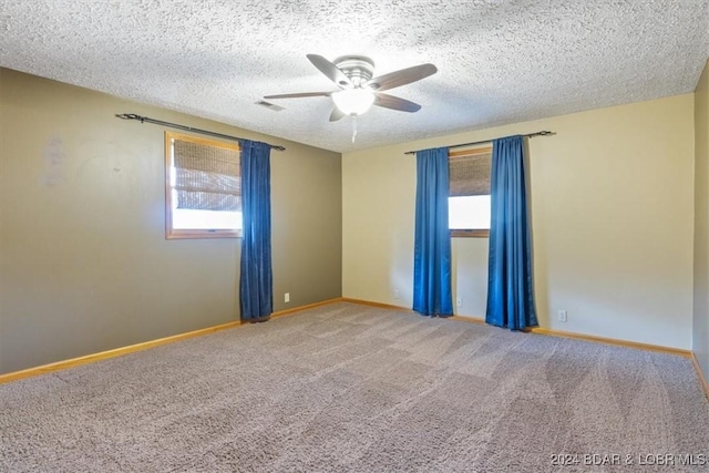 carpeted empty room featuring ceiling fan, plenty of natural light, and a textured ceiling