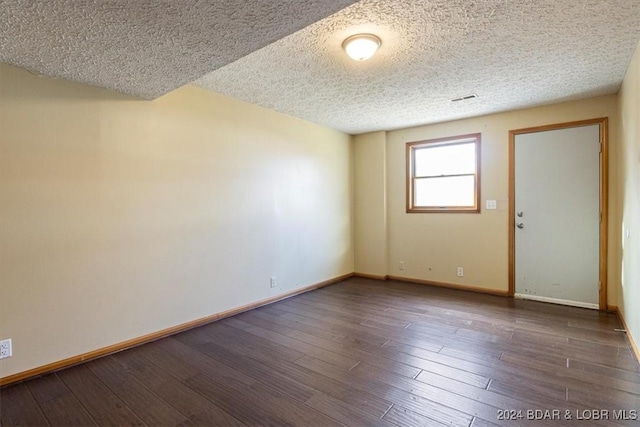 unfurnished room with a textured ceiling and dark wood-type flooring