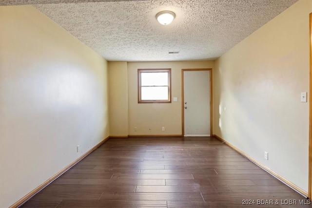 unfurnished room featuring a textured ceiling and dark hardwood / wood-style floors