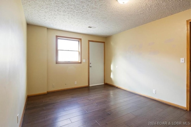 spare room with a textured ceiling and dark hardwood / wood-style floors