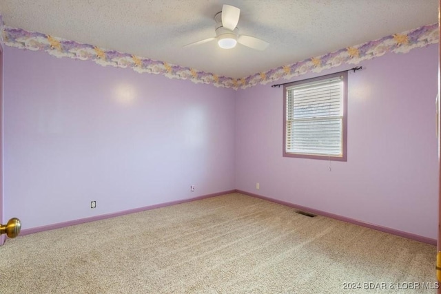 spare room featuring carpet, ceiling fan, and a textured ceiling