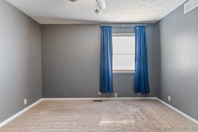 empty room with ceiling fan, carpet floors, and a textured ceiling