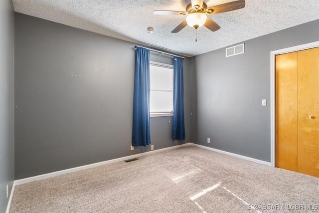 carpeted spare room featuring ceiling fan and a textured ceiling