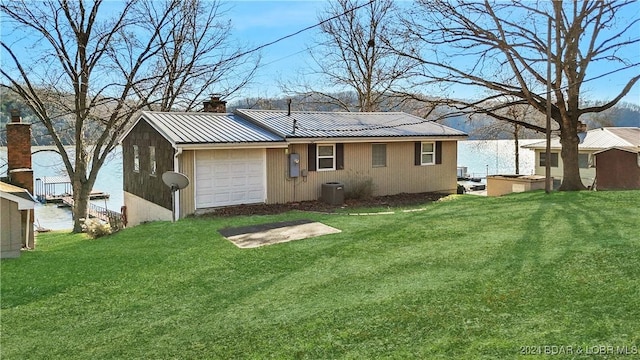 rear view of house with central air condition unit, a yard, and a garage