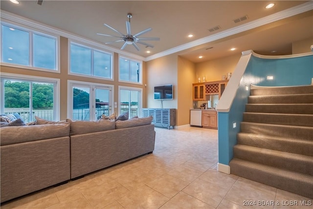 tiled living room with a high ceiling, ceiling fan, and crown molding