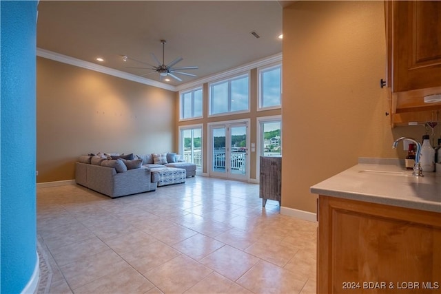 tiled living room with french doors, a towering ceiling, ceiling fan, crown molding, and sink