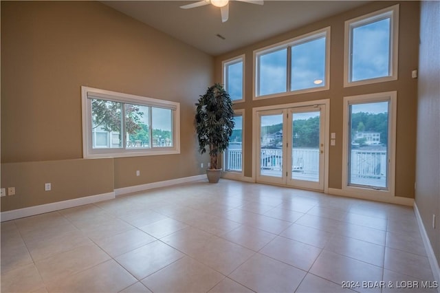 tiled empty room featuring high vaulted ceiling, ceiling fan, and a wealth of natural light