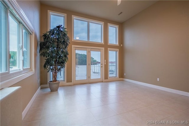 doorway to outside featuring a wealth of natural light, high vaulted ceiling, and light tile patterned floors